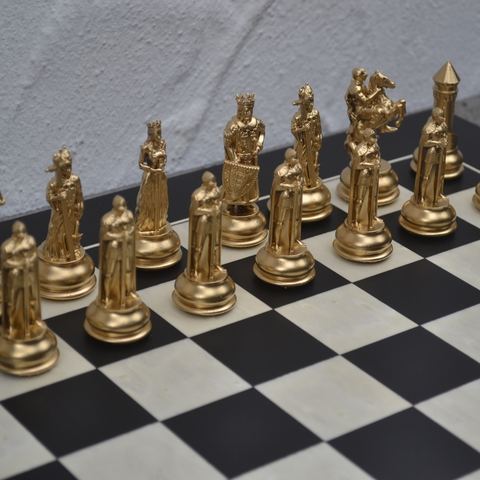 Aufgestellte Reihe vergoldeter Schachfiguren auf dem Brett