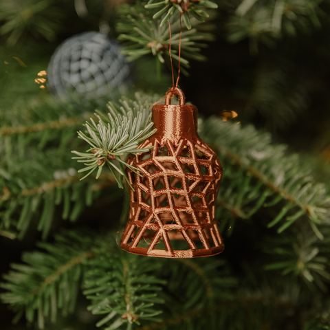 Kupferfarbene Glocke mit Gittermuster am Baum